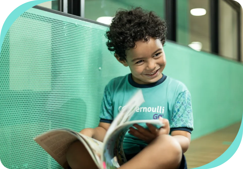 Estudante da Educação Infantil do Bernoulli Go com seu material didático em mãos.