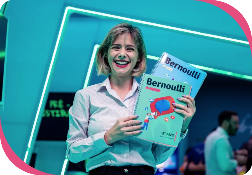 Educadora sob filtro esverdeado, sorrindo para a câmera enquanto mostra o material didático do Bernoulli