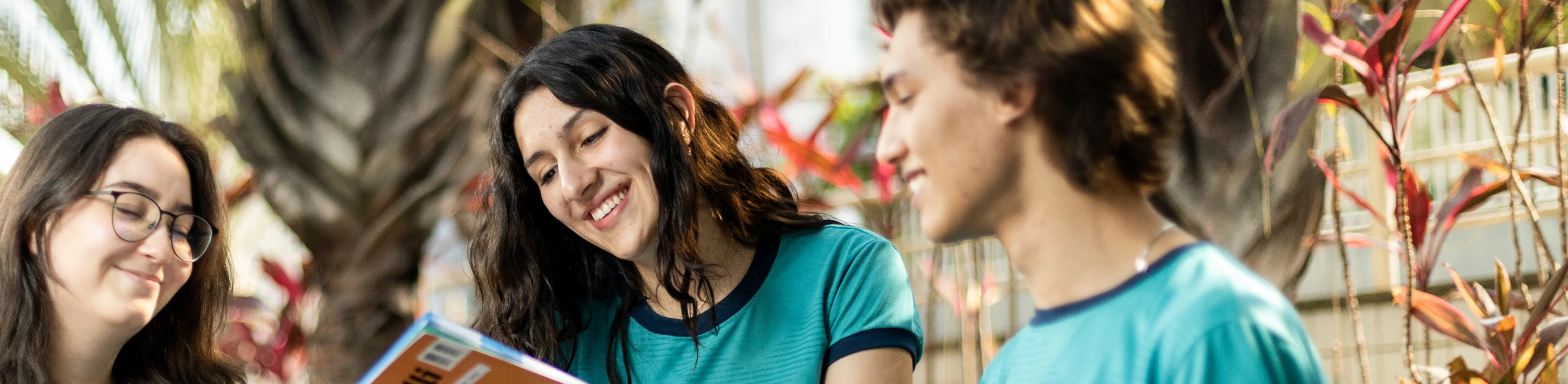 Três estudantes sorrindo enquanto utiliza o material físico e digital do Bernoulli