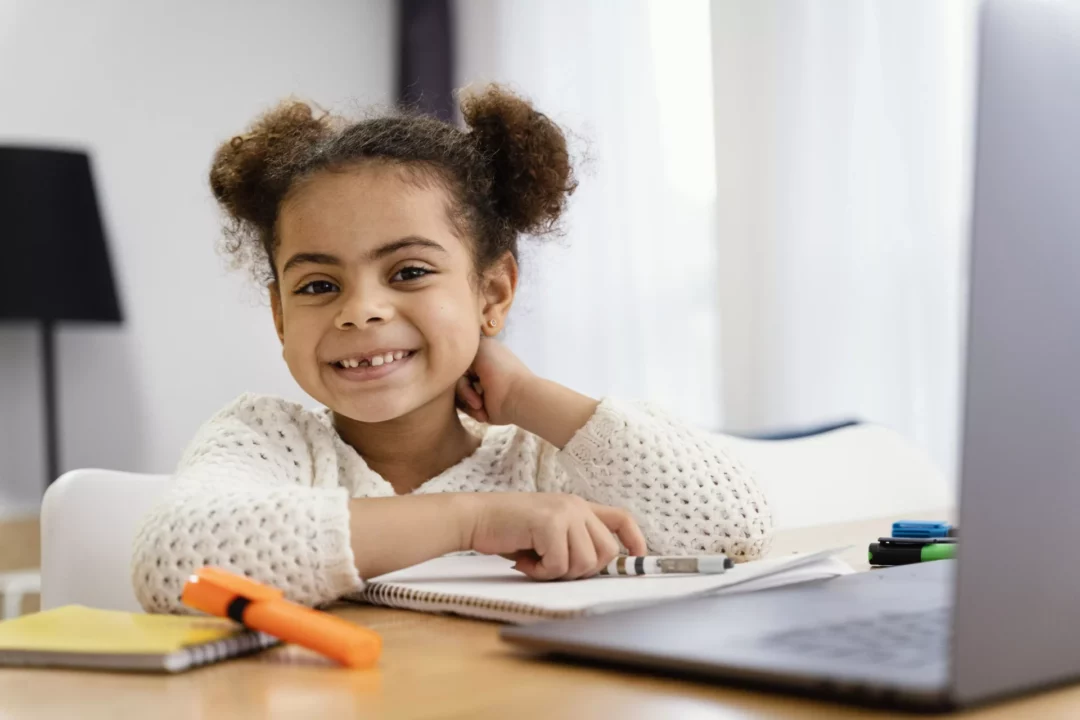 Menina sorridente em casa com laptop durante lição de casa