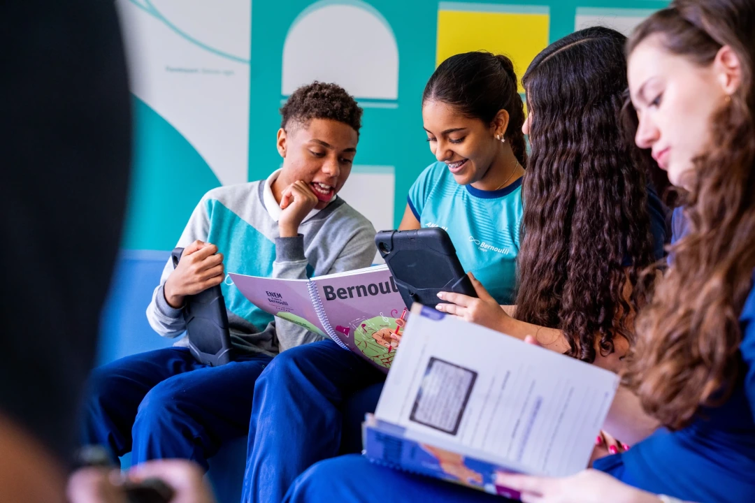 Grupo de alunos em ambiente escolar utilizando tablets e material didático durante atividade